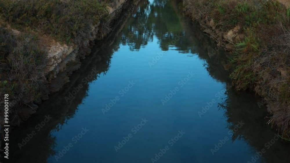Water Channel, Reflection of Clear Blue Sky in Water, Lush Green Vegetation Along Banks Creates Cerene and Peaceful Landscape.