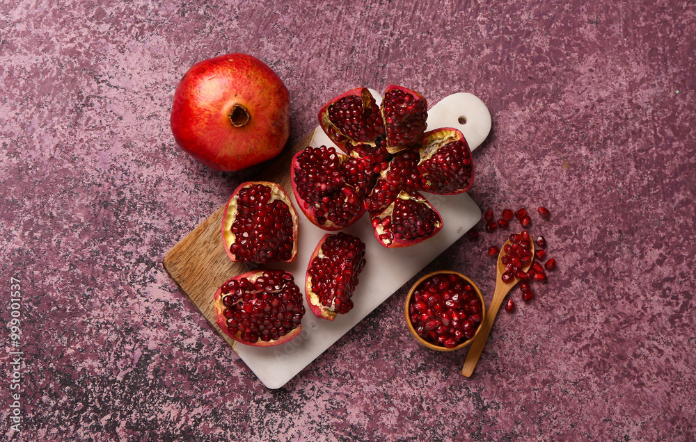 Board with fresh pomegranates and bowl of seeds on purple background Board with fresh pomegranates and bowl of seeds on purple background
