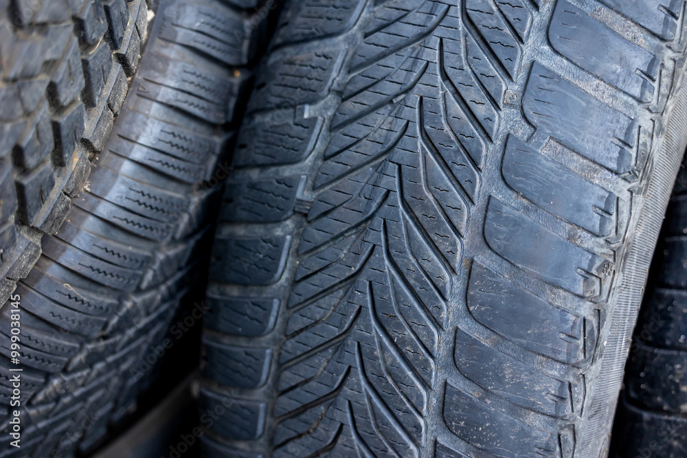 Worn and damaged tread of old tires lying in a landfill. Decreased road safety and environmental pollution from rubber waste