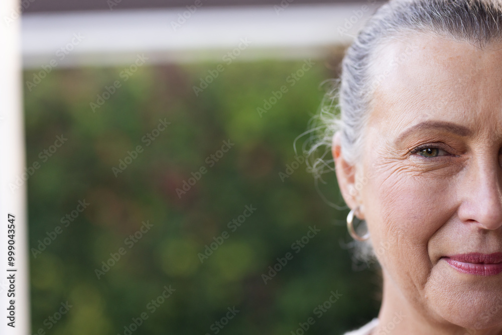 Smiling senior woman with hoop earrings enjoying outdoor time in garden, copy space, at home Smiling senior woman with hoop earrings enjoying outdoor time in garden, copy space, at home