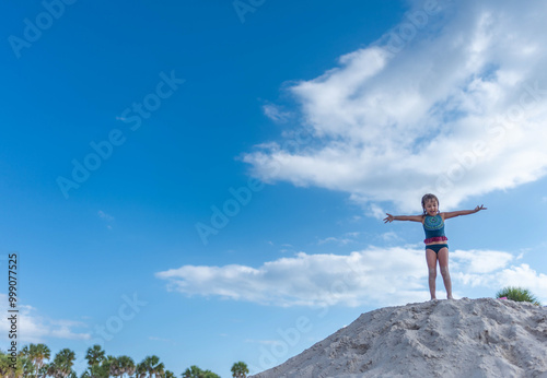 Young girl on top of a sound pile with arms open, copy space