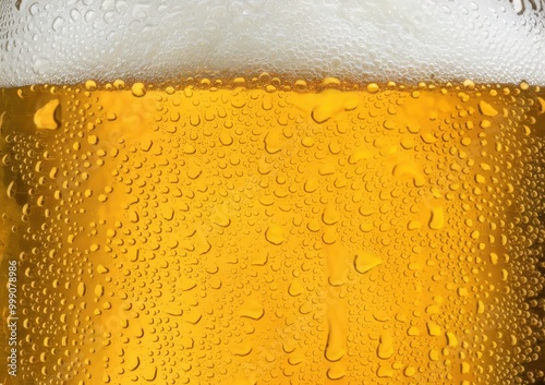 Close-up of a frothy, cold glass of golden beer with condensation.