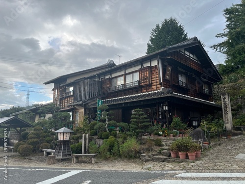 Photography Traditional Japanese wooden inn with manicured garden and stormy skies along his