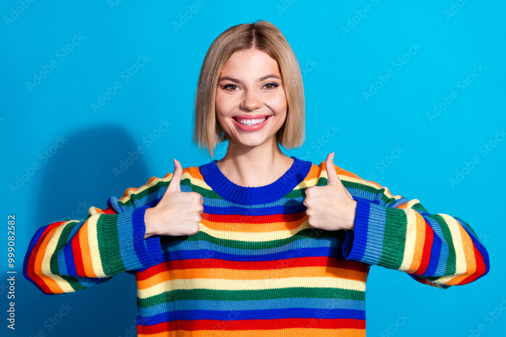 Photo of nice young woman show thumb up wear striped sweater isolated on blue color background Photo of nice young woman show thumb up wear striped sweater isolated on blue color background