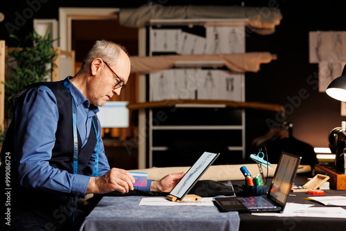 Fashion designer ready to buy tailoring materials he needs for upcoming customer sartorial comission after finding inspiration online. Senior couturier purchasing sewing instruments with credit card