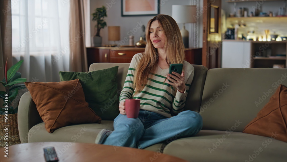 Girl relaxing coffee cup holding smartphone. Woman enjoy beverage sitting home Girl relaxing coffee cup holding smartphone. Woman enjoy beverage sitting home