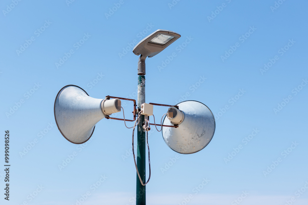 Public address system mounted on a streetlight under a clear blue sky Public address system mounted on a streetlight under a clear blue sky