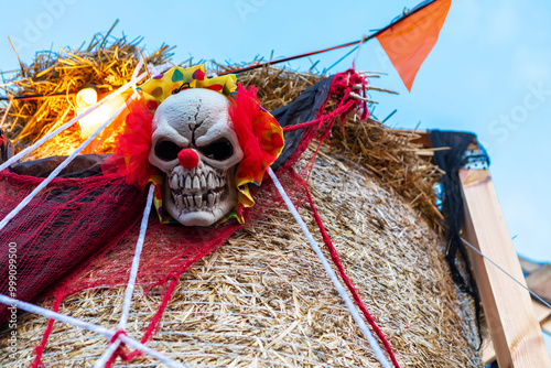 Spooky clown face on a creepy scarecrow with red flag waving on hay bale photo