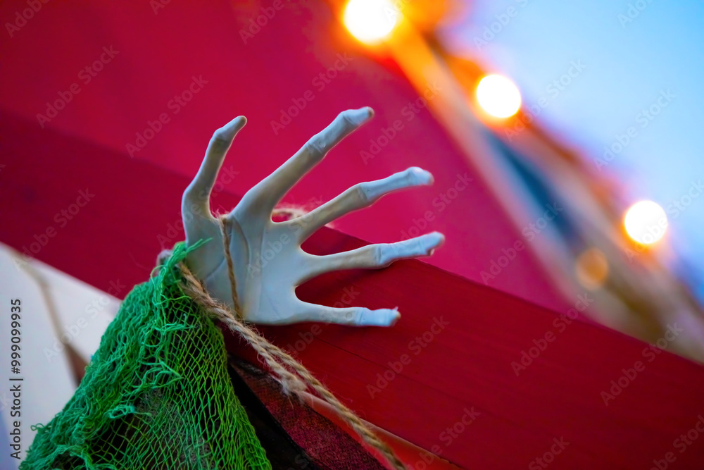 Φωτογραφία White skeletal hand reaching out from a red wall with a fishing net on the left side of the hand