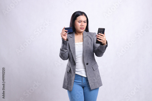 beautiful young office lady asia disgusted to smartphone hold cellphone smartphone and hold credit debit member card wearing gray suit isolated on white background. for communication, finance