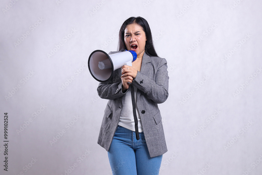 formal beautiful young girl screaming angry both hands holding loudspeaker megaphone right wearing grey suit isolated on white background. fashion, lifestyle, advertising, sale, company concept formal beautiful young girl screaming angry both hands holding loudspeaker megaphone right wearing grey suit isolated on white background. fashion, lifestyle, advertising, sale, company concept