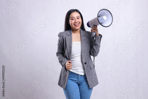 beautiful young woman shouting formal cheerful to camera hand holding megaphone loudspeaker and holding wearing grey suit isolated on white background. fashion concept, lifestyle, advertising,discount