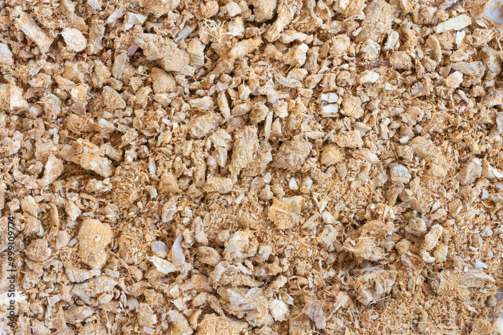 A top view image of a dried and ground ginger pieces placed on a flat surface. A top view image of a dried and ground ginger pieces placed on a flat surface.