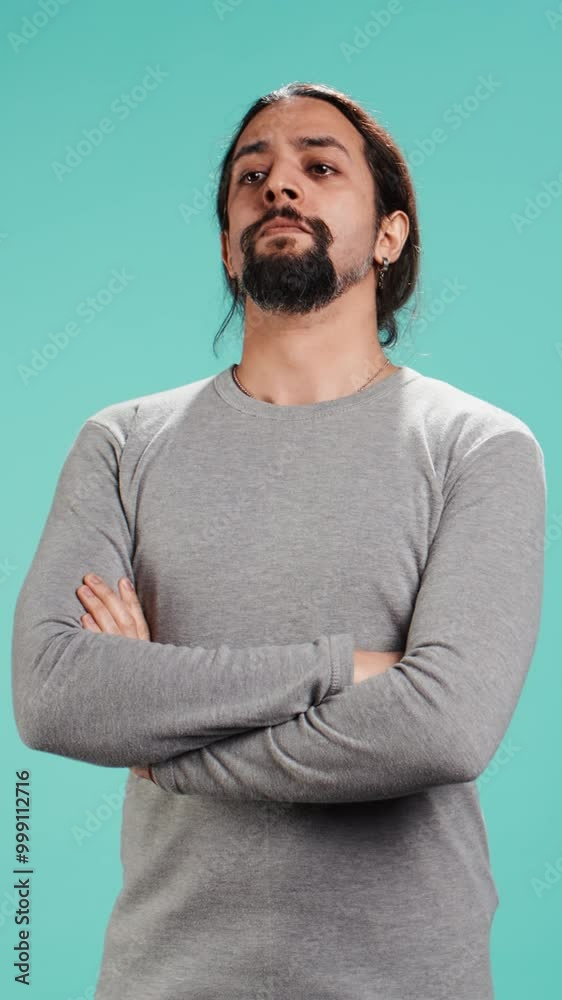 Vertical video Grumpy man with sulking facial expression crossing arms, feeling annoyed, isolated over studio background. Portrait of irate person in bad mood feeling frustrated after argument, camera Vertical video Grumpy man with sulking facial expression crossing arms, feeling annoyed, isolated over studio background. Portrait of irate person in bad mood feeling frustrated after argument, camera