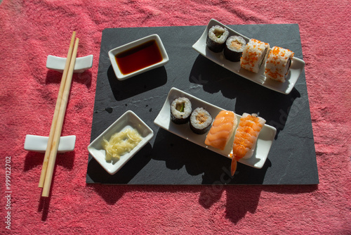 Sushi on white porcelain, wooden chopsticks and black sauce photo