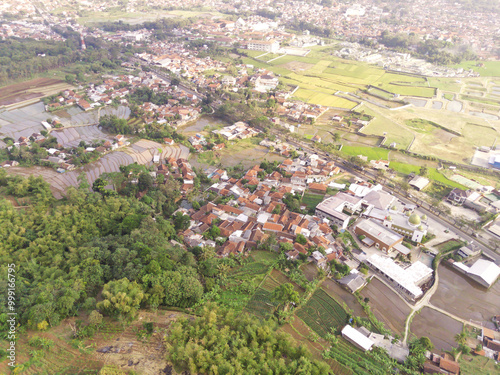 Photography of residential district from aerial perspective. A small village surrounded by green rice fields in Bandung Regency - Indonesia. Residential Settlement. Rural Scenery. Aerial Photography