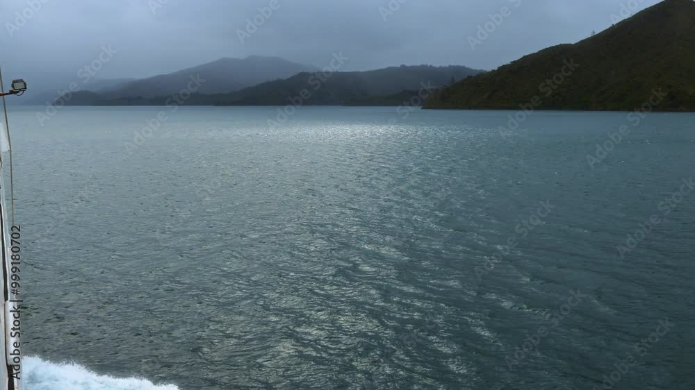 View from a boat moving toward green mountains in the distance. The turquoise water ripples from the boat’s movement, creating gentle waves as the boat nears the shore. Stunning New Zealand scenery. View from a boat moving toward green mountains in the distance. The turquoise water ripples from the boat’s movement, creating gentle waves as the boat nears the shore. Stunning New Zealand scenery.