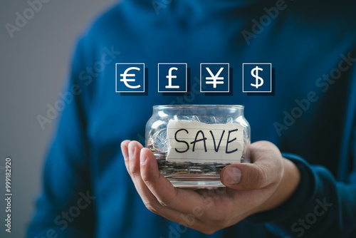 Hand holding a jar labeled 'SAVE' with currency symbols above, representing saving money and financial planning. photo