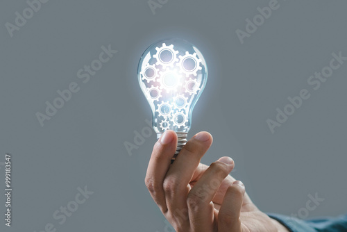 A hand holding a glowing light bulb with gears inside, symbolizing innovation and creativity in technology and ideas.