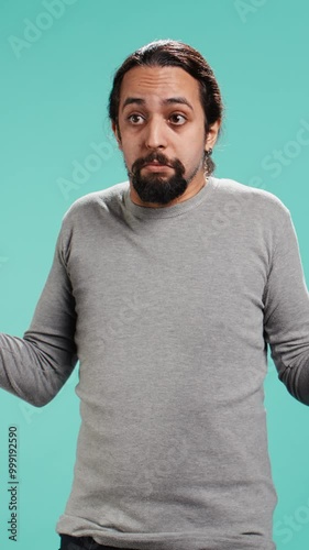Vertical video Man shrugging shoulders, unable to provide answer, having detached apathy facial expression. Apathetic person doing hand gesturing showing lack of knowledge, studio background, camera B