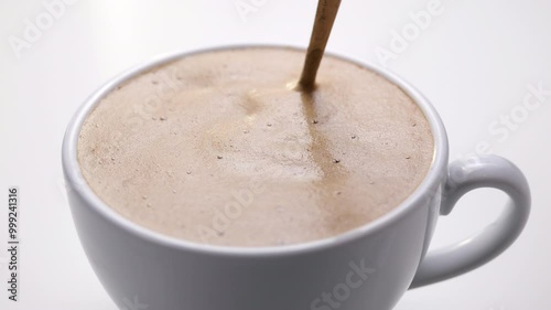 Stirring the smooth surface of freshly made coffee, a perfect start to any day. The delicate foam atop a rich, brewed coffee, inviting a warm sip of relaxation.