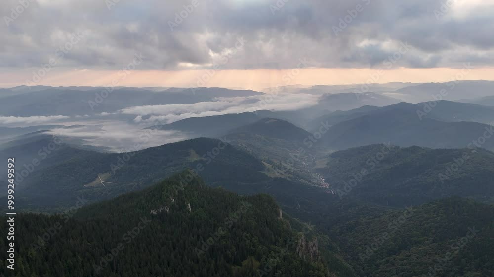 Drone view of sunrise over forested mountains and low clouds in Ceahlau moutain Drone view of sunrise over forested mountains and low clouds in Ceahlau moutain