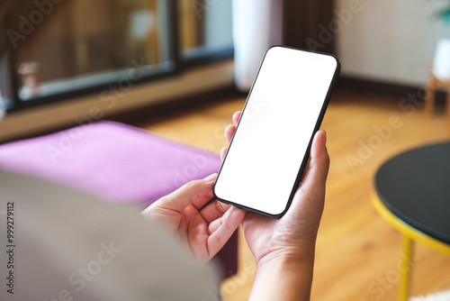 Obraz na płótnie Mockup image of a woman holding mobile phone with blank desktop white screen at home w salonie