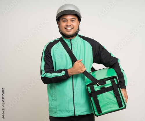 Young asian rider wearing green jacket uniform and helmet various action holding a lot of paper parcel delivery box to customer. Man service worker Courier and shipping food delivery service. photo