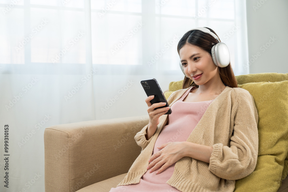 Happy pregnant young woman holding headphone on her womb at home, relaxed young asian mother let her fetal listening to music, family planning and pregnancy with insurance for child health. Happy pregnant young woman holding headphone on her womb at home, relaxed young asian mother let her fetal listening to music, family planning and pregnancy with insurance for child health.