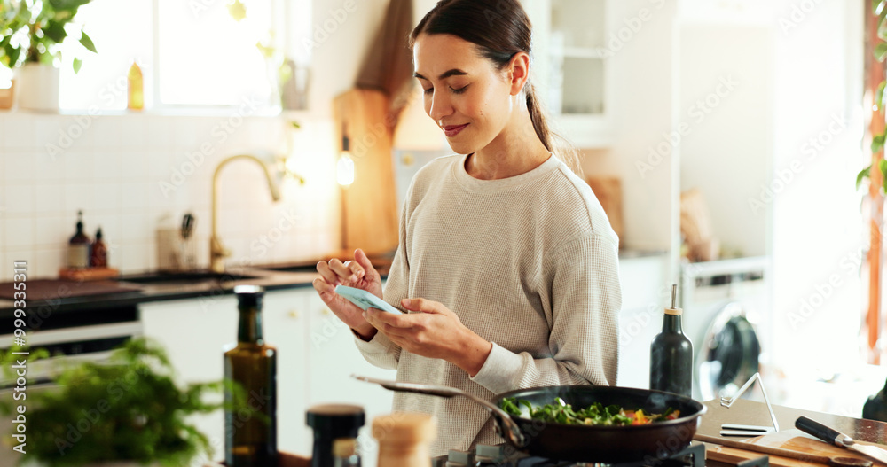 © HockleyM3/peopleimages.com - Woman, cooking and phone by stove in home for healthy salad recipe, meal prep and ingredients research. Nutrition influencer, food blogger or vegan chef with tech for social media tutorial in kitchen