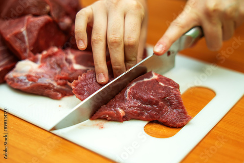 skilled hand expertly slices fresh beef into precise pieces, showcasing the art of butchery. The glistening meat reflects mastery and tradition in culinary craftsmanship