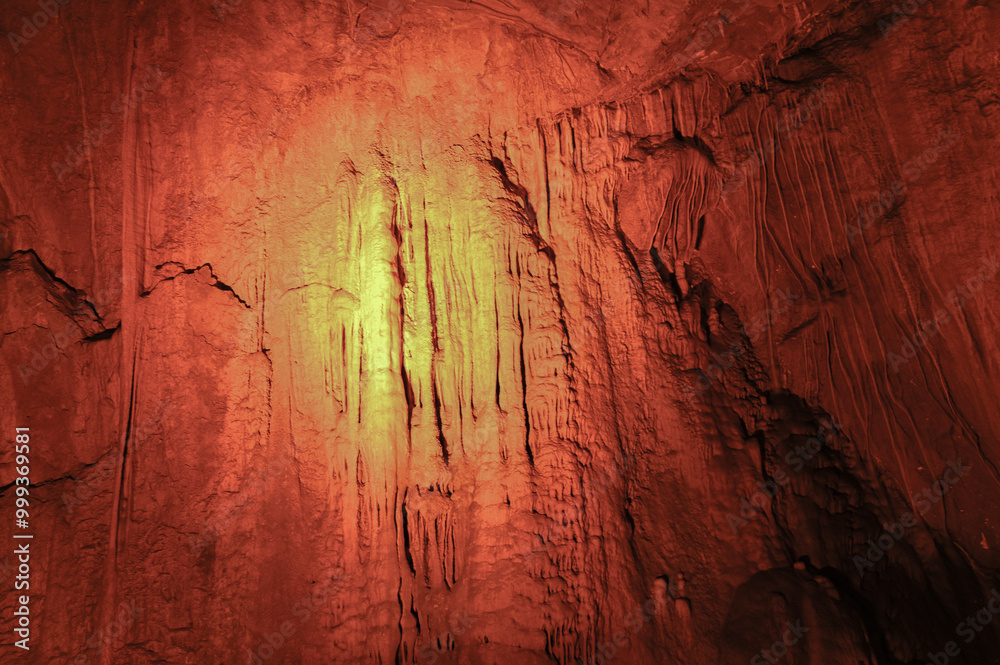 Naklejka premium Stalactites hanging from the vaults of the cave illuminated by artificial light