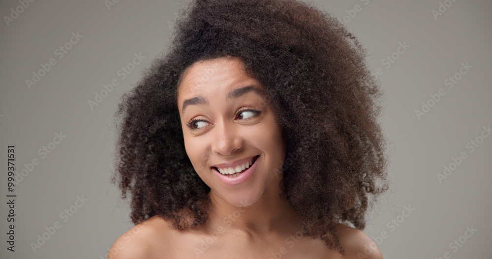 Beauty and Healthcare - Beautiful African American woman with curly afro hairstyle and clear, healthy skin looks playfully to the side with a bright toothy smile Beauty and Healthcare - Beautiful African American woman with curly afro hairstyle and clear, healthy skin looks playfully to the side with a bright toothy smile
