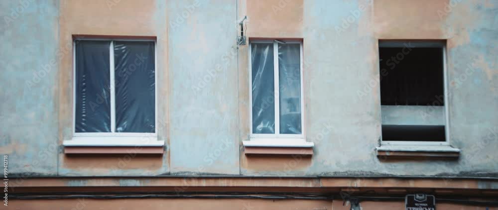 Shot of multi-storey building with broken windows after shelling of city. Horizontal shot of building with flag. War. Daytime. Street. City Shot of multi-storey building with broken windows after shelling of city. Horizontal shot of building with flag. War. Daytime. Street. City