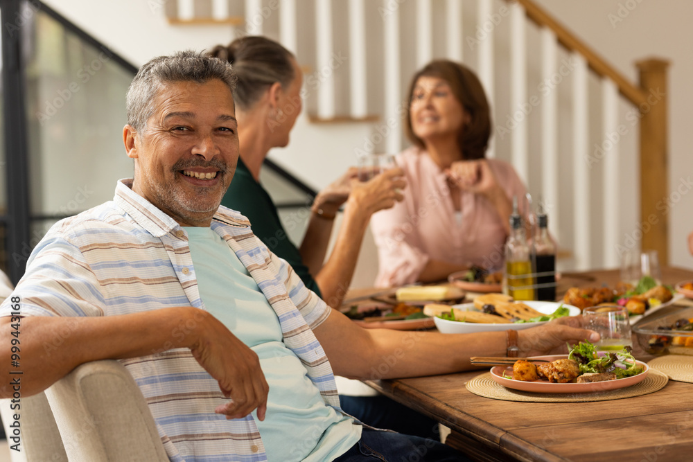 Smiling senior man enjoying meal with diverse friends at dining table, sharing laughter and food, at Smiling senior man enjoying meal with diverse friends at dining table, sharing laughter and food, at