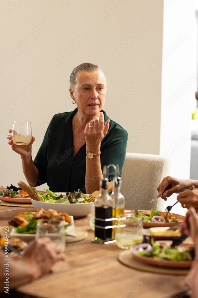 Enjoying meal, senior senior woman talking with diverse friends at dining table, at home Enjoying meal, senior senior woman talking with diverse friends at dining table, at home