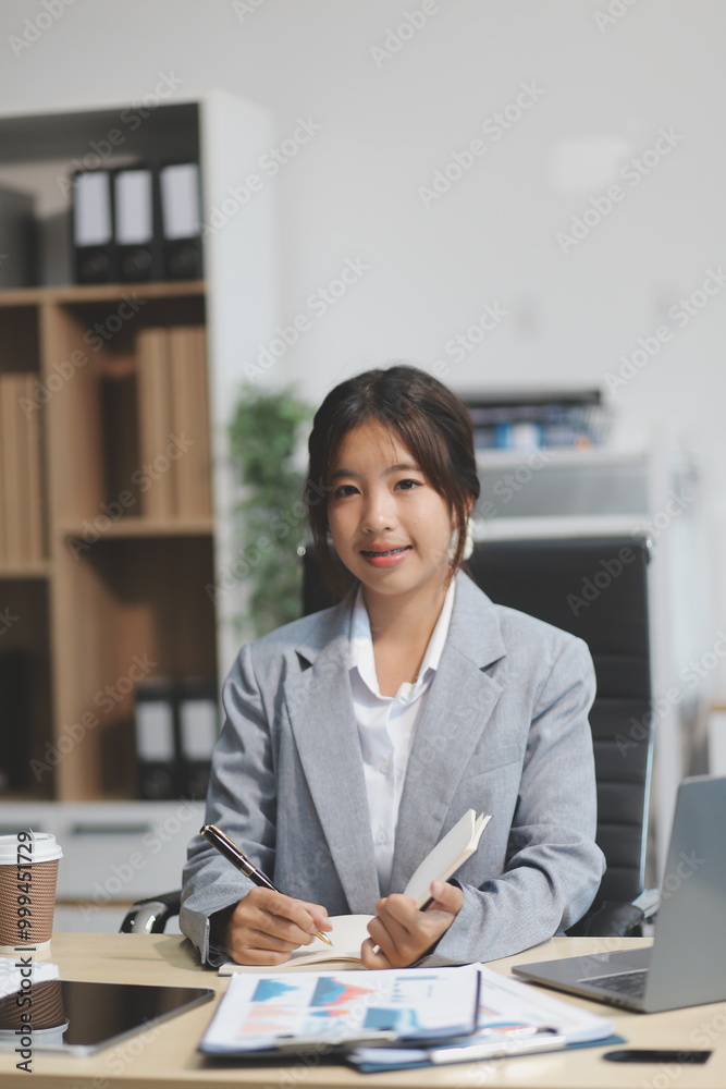 Successful Asian businesswoman smiling using laptop computer and holding coffee cup at office. Confident Asia businesswoman sitting happily in the office. Successful Asian businesswoman smiling using laptop computer and holding coffee cup at office. Confident Asia businesswoman sitting happily in the office.