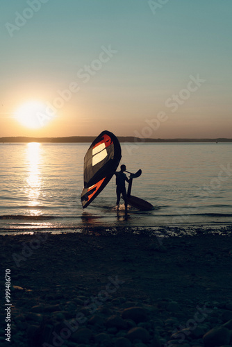 Man athlete comes out of the water with wing foil equipment. photo