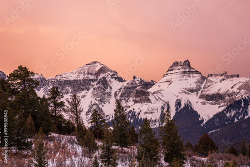 pine tree mountain ridge in front of snow-covered mountain peaks