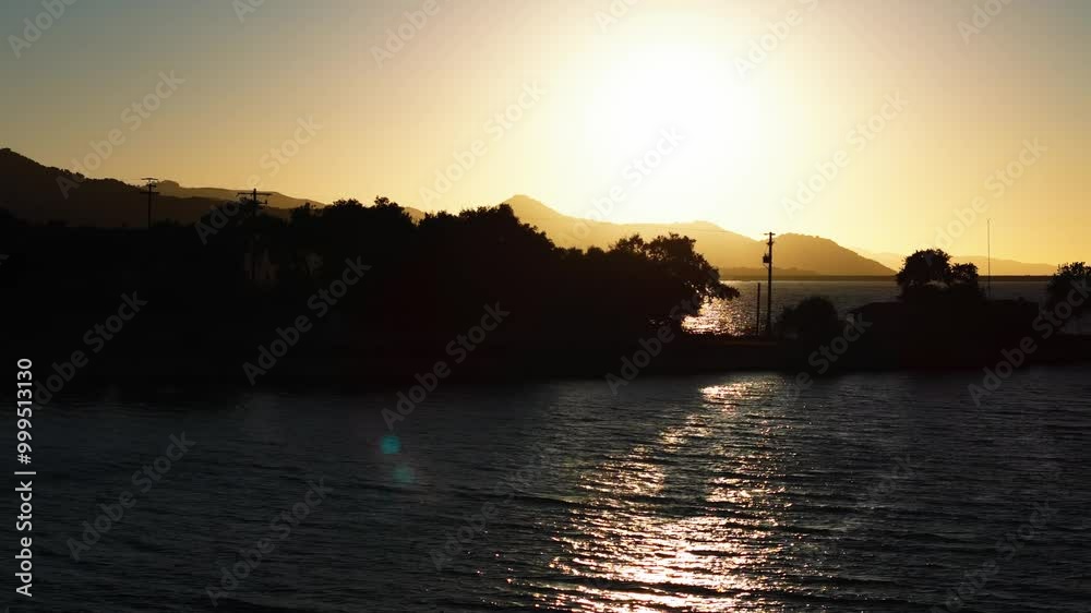 Arial view on sun coming trough the trees shiluette on a island in a lake watter Sunset, Drone, 4k, California