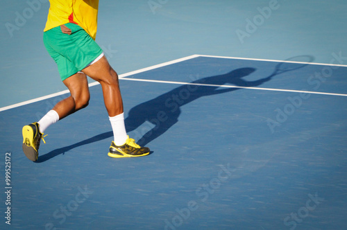 Tennis player running and hitting ball with forehand on blue court photo