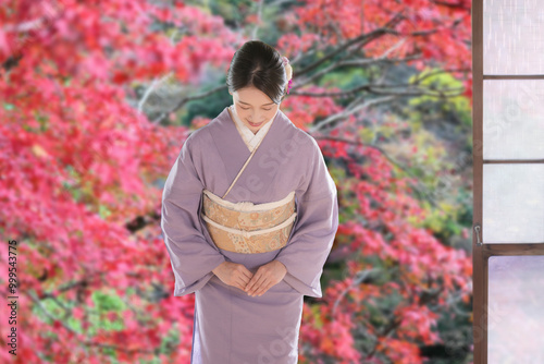 Fotografie 紅葉の背景でお辞儀する着物を着た日本人女性　日本の観光や旅行のおもてなしイメージ