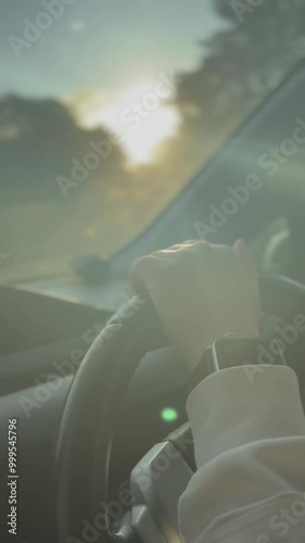 Close-up of a hand on a wheel, driving on a sunset highway in Auckland, New Zealand.