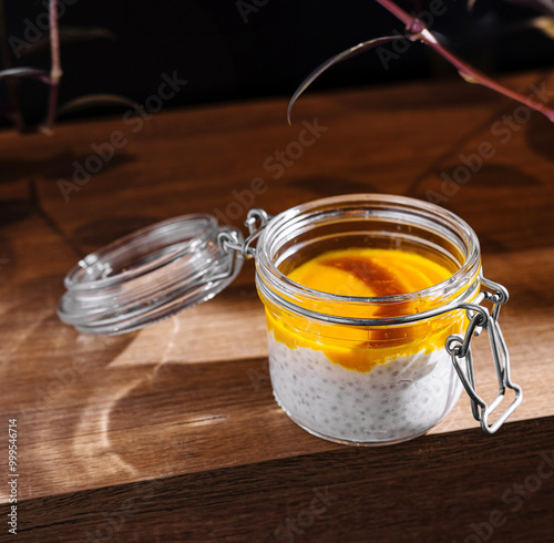 Chia pudding with mango puree in glass jar on wooden table is waiting for client of cafe