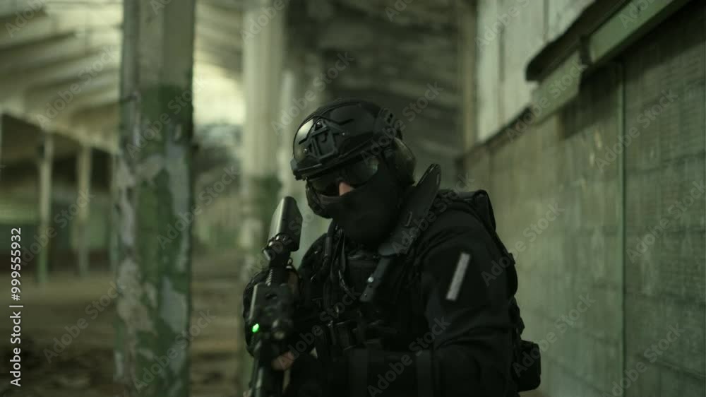 Portrait follow shot of a SWAT operator in black gear and an assault rifle with a green laser securing an abandoned warehouse Portrait follow shot of a SWAT operator in black gear and an assault rifle with a green laser securing an abandoned warehouse