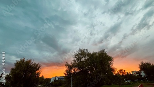 sky with orange sunset on background of white house trees and street lamp . autumn evening