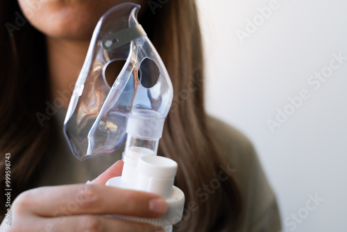 фотографія Woman holding breathing inhaler, nebulizer, in hand preparing for home procedure