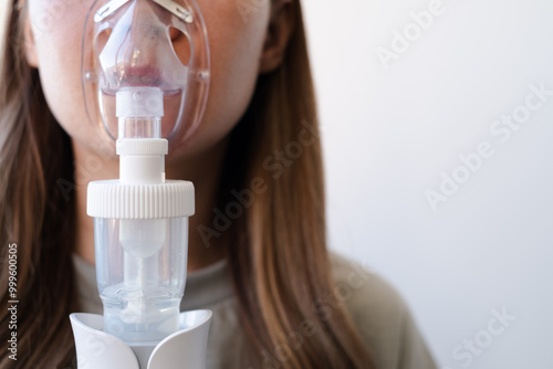 A girl breathes with the help of a nebulizer inhaler for the treatment of colds and coughs during the cold season photo