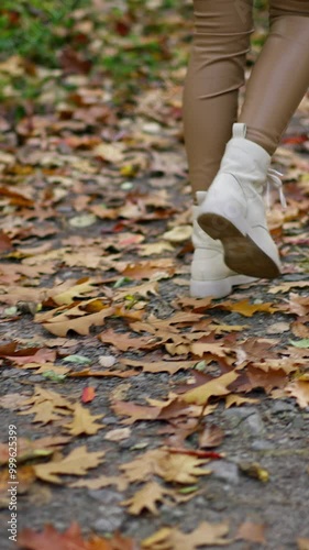 Wallpaper Mural Female in tight beige leggings and white boots walks quickly by the path in the park. Unrecognized lady taking a stroll on autumn day. Torontodigital.ca