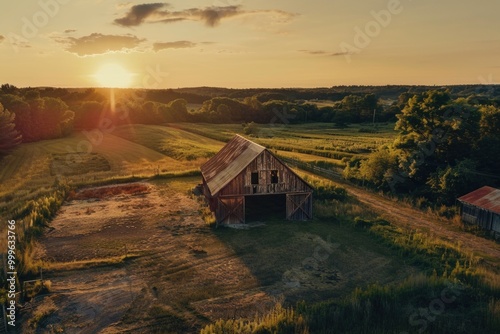 Aerial view of a barn standing alone in a green field with rolling hills in the background